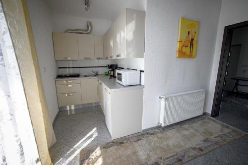 una pequeña cocina con armarios blancos y microondas en Appartement in Naterki mit Terrasse, Garten und Grill en Naterki