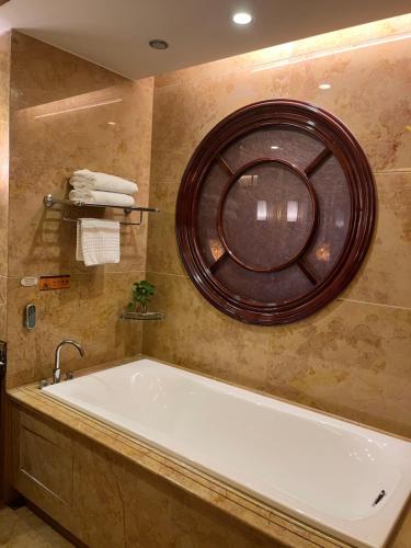 a bath tub in a bathroom with a round mirror at Days Hotel & Suites China Town---Five minutes to reach Changsha Station, the metro Line 2 & Line 6 are nearby,free gym & laundromat,Chinese and Western buffet breakfast is offered on the 31st floor in Changsha