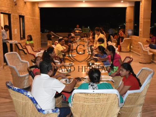 un grupo de personas sentadas alrededor de una mesa comiendo en Hotel Grand Heritage Jaisalmer, en Jaisalmer