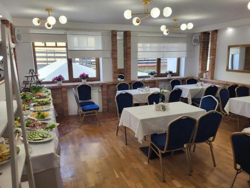 een restaurant met witte tafels en blauwe stoelen bij Pensjonat Stach in Ustka