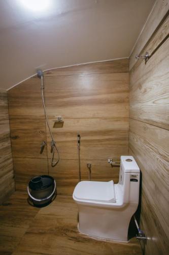 a bathroom with a toilet in a room with wooden walls at Luxury Houseboat in Alleppey