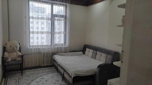 Habitación pequeña con cama y osito de peluche en Уютная квартирка в центре Душанбе en Dushanbe