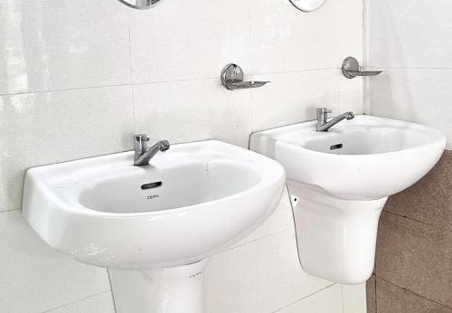 La salle de bains est pourvue d'un lavabo blanc et de toilettes. dans l'établissement Campper Campwoody Munnar, à Munnar