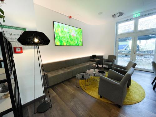 uma sala de estar com um sofá e uma televisão na parede em HOLI City Apart Hotel Berlin em Berlim