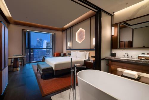 a hotel room with a bed and a bath tub at Grand Barony Jinan CBD in Jinan