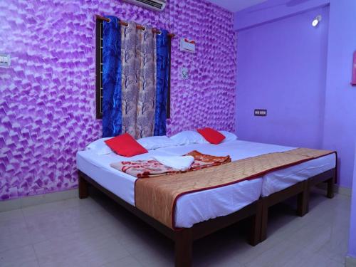 um quarto com uma cama com uma parede roxa em La nest residency em Pondicherry