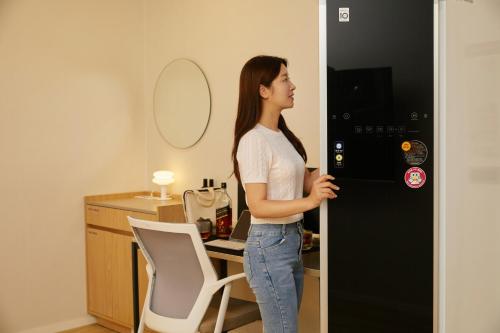 a woman standing in front of a black refrigerator at The Hyoosik Aank Hotel Ilsan Tanhyeon in Goyang