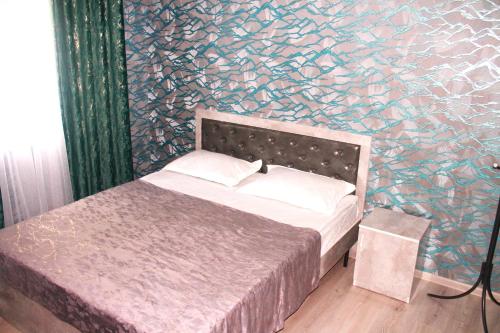 1 dormitorio con 1 cama y pared con 1 plaza en Гостевой дом Эверест en Arkit