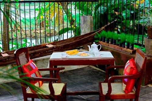 a table and two chairs with a tea pot on it at Riverdale Homestay Kumarakom by LexStays in Kumarakom