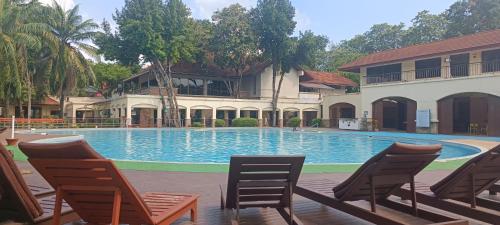 - une piscine avec des chaises en face d'un bâtiment dans l'établissement Kanchanaburi Modern Home, à Kanchanaburi