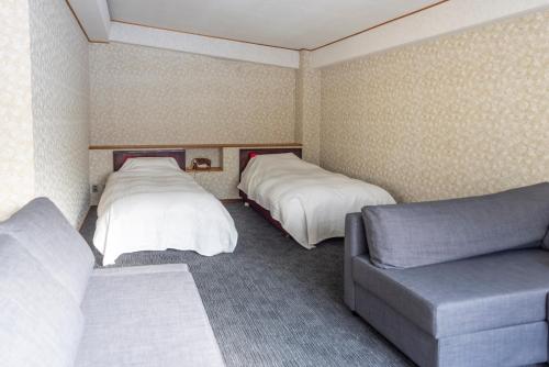 a hotel room with two beds and a couch at Kogakuro in Myoko