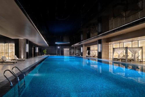 a large swimming pool with blue water in a building at Grand Barony Jinan CBD in Jinan