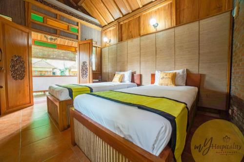 Cette chambre comprend 2 lits et une fenêtre. dans l'établissement Joglo Garut Cottage Syariah by My Hospitality, à Bojongsalam