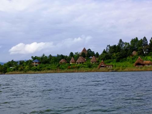 eine Gruppe von Häusern am Ufer eines Wasserkörpers in der Unterkunft Paradise Eco-Hub in Kabale