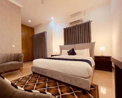 a bedroom with a large bed and a chair at Rhodium Hotel ONE in Islamabad