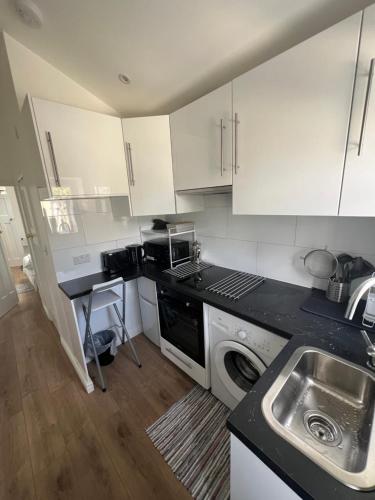 una cocina con armarios blancos y fregadero en Cosy Studio Apartment, Flat in London, en Chislehurst