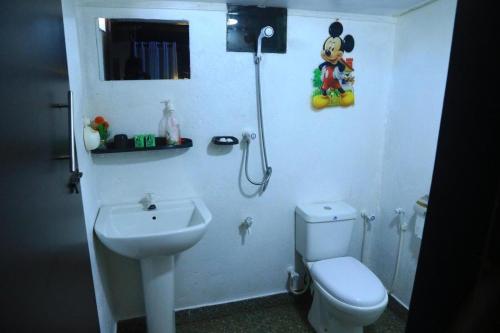 a white bathroom with a toilet and a sink at Woody Cabana in Trincomalee
