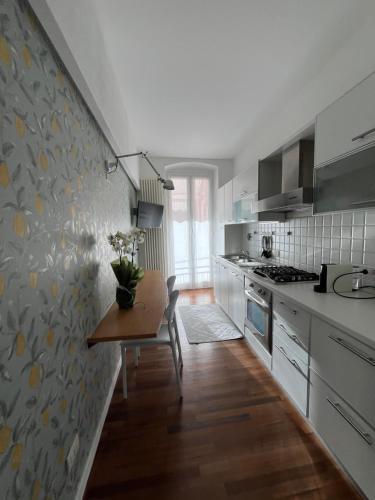 ポルトヴェーネレにあるAbout Italy Holiday Rooms and Apartmentsの白いキャビネットと花瓶付きのテーブルが備わるキッチン