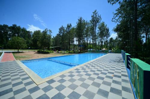 uma piscina num parque com piso em azulejo em SIPAYI RESORT COORG em Kushalanagar