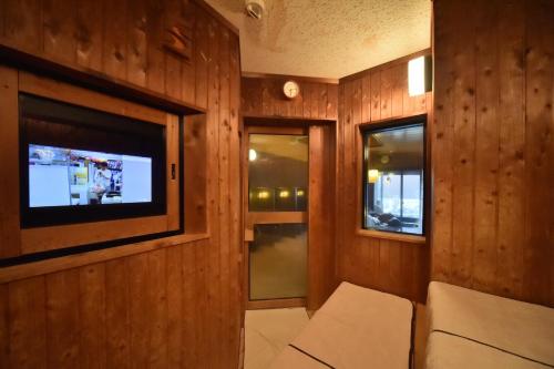 a room with a tv and a couch and windows at Dormy Inn Tomakomai in Tomakomai