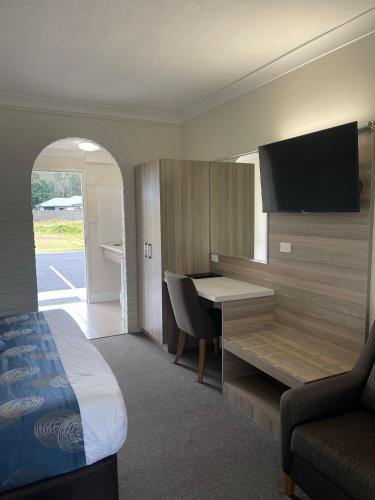 a hotel room with a bed and a desk with a computer at Aston Motel Yamba in Yamba