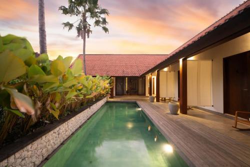 a villa with a swimming pool and a house at Rarama Living Studio in Kerobokan
