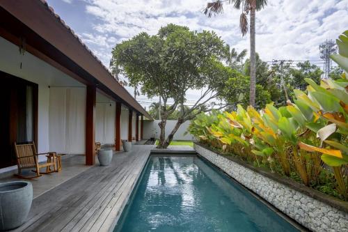 uma casa com uma piscina e um deque de madeira em Rarama Living Studio em Kerobokan