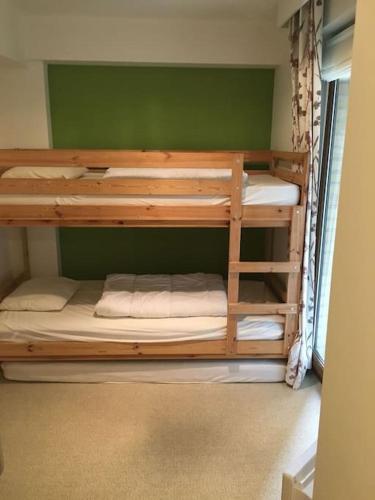 2 Etagenbetten in einem Zimmer mit grüner Wand in der Unterkunft Appartement cosy au cœur du Zoute près de la plage in Knokke-Heist