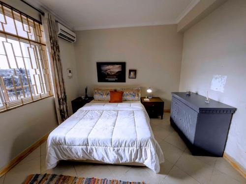 a bedroom with a large bed and a large window at Olive Escapes in Dar es Salaam