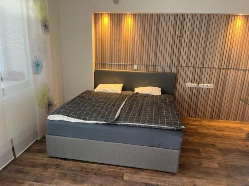 1 dormitorio con 1 cama y pared de madera en Eisenstrassen Apartment en Ybbsitz