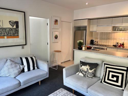 a living room with two couches and a kitchen at Lovely 2 bedrm apartment in Auckland's viaduct in Auckland
