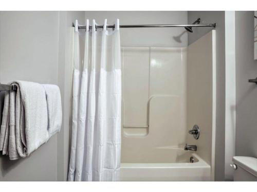 baño con ducha con cortina blanca en Beautiful 2BR 2BA In The Block by CozySuites, en Indianápolis