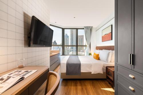 a bedroom with a bed and a desk with a television at Dash Living on Hollywood in Hong Kong