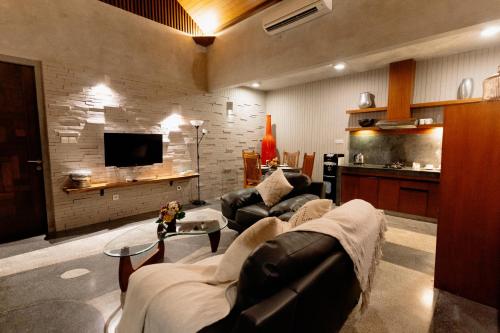 ein Wohnzimmer mit einem Sofa und einem TV in der Unterkunft Bracha Villas Bali - CHSE Certified in Seminyak