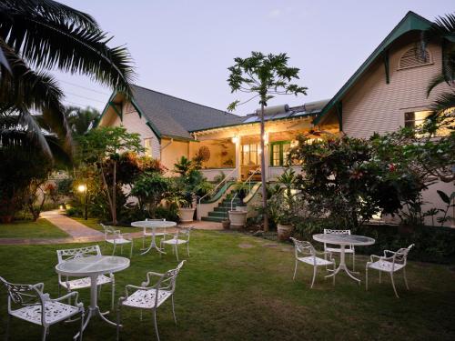 a group of tables and chairs in front of a house at The Historic Wailuku Inn Maui in Wailuku