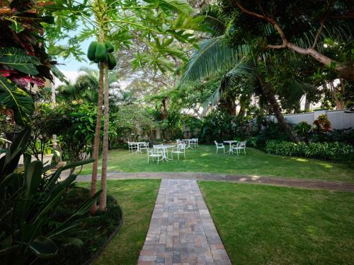 a garden with tables and chairs on a lawn at The Historic Wailuku Inn Maui in Wailuku