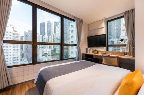 a bedroom with a large bed and large windows at Dash Living on Hollywood in Hong Kong