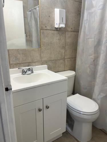 een badkamer met een wastafel, een toilet en een spiegel bij Kp Paradise in North Miami