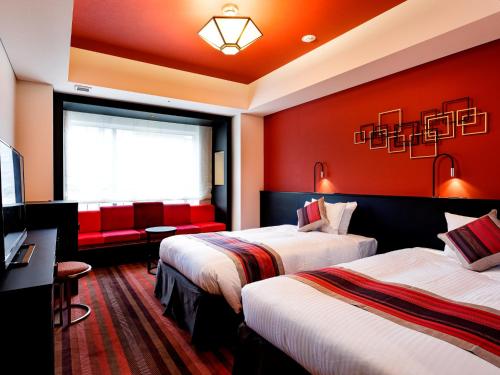 two beds in a hotel room with red walls at Hotel Dans Le Coeur Osaka Umeda in Osaka