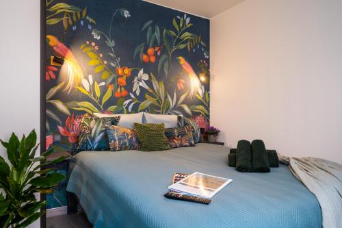 a bedroom with a blue bed with a painting on the wall at Green Garden & Parking Apartments in Rīga