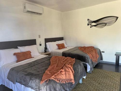Cette chambre comprend deux lits et un ventilateur mural. dans l'établissement Bungalow Ballena c/vistas increíbles al Océano Pacífico, à Perihuete
