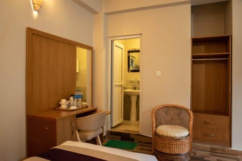 a bedroom with a bed and a desk and a chair at Busy Bee Resort, Pokhara in Pokhara