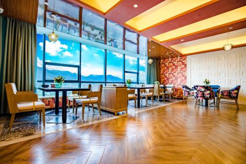 un restaurante con mesas, sillas y ventanas grandes en Mehood Theater Hotel, Lhasa, en Lhasa