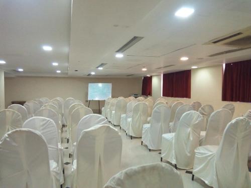 an empty room with white chairs and a screen at Hotel Western Gatz in Theni