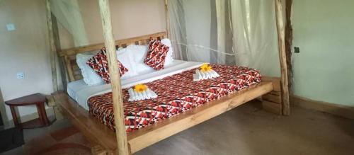 a bedroom with a wooden bed with pillows on it at Bwindi My Home in Kinkizi