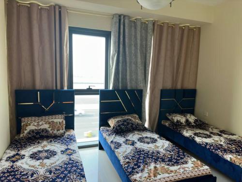 two beds in a room with a window at Luxurious Apartment in Dubai