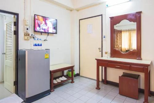 a kitchen with a refrigerator and a table and a mirror at Khelang Nakorn Hotel in Lampang