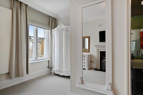 Dieses weiße Zimmer verfügt über einen Spiegel und einen Kamin. in der Unterkunft Stunning 2 king size beds 2 bath- sleeps 5 in Earls Court in London