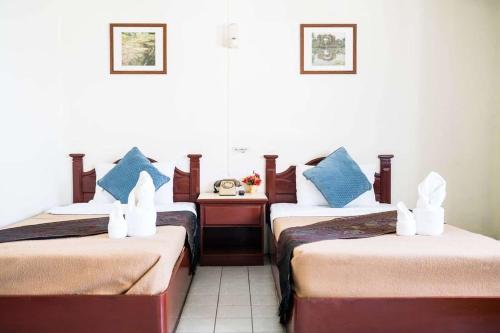 a hotel room with two beds with blue pillows at Khelang Nakorn Hotel in Lampang