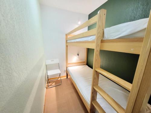 a small room with two bunk beds and a chair at Résidence Le Parc Des Airelles - 2 Pièces pour 6 Personnes 984 in Les Orres